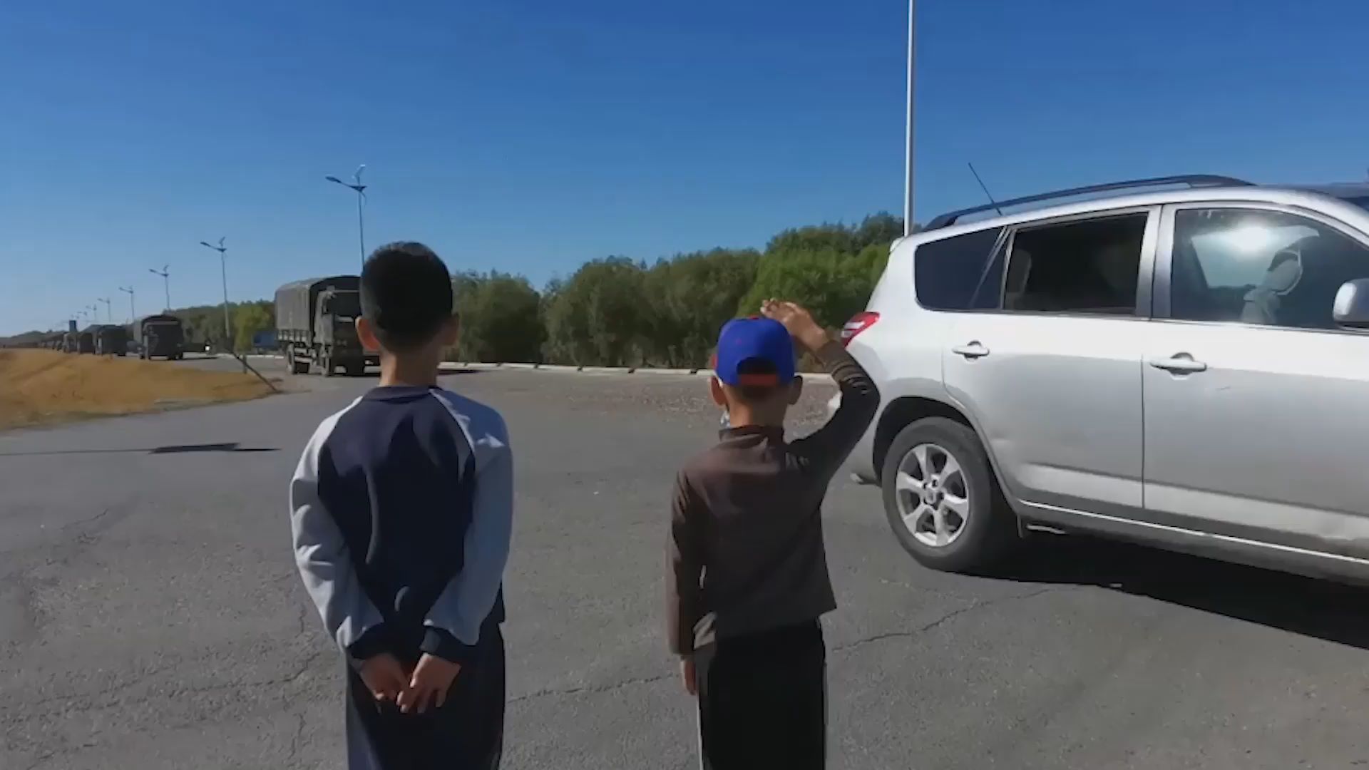 兩名男孩向路過軍車敬禮，車輛鳴笛回應